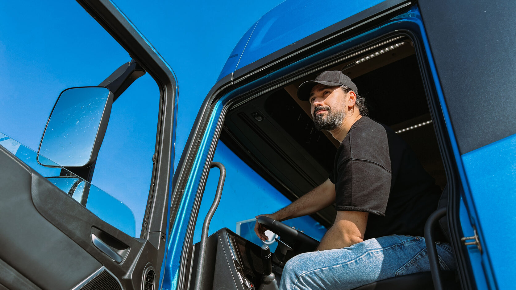 Driver seated in the cab of a blue truck